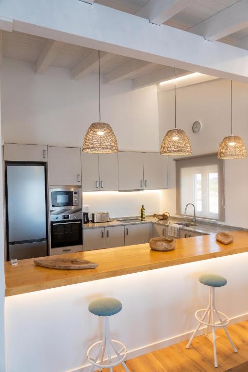a kitchen with white cabinets and a counter with stools at Herdade do Cascalhar in Vila do Bispo