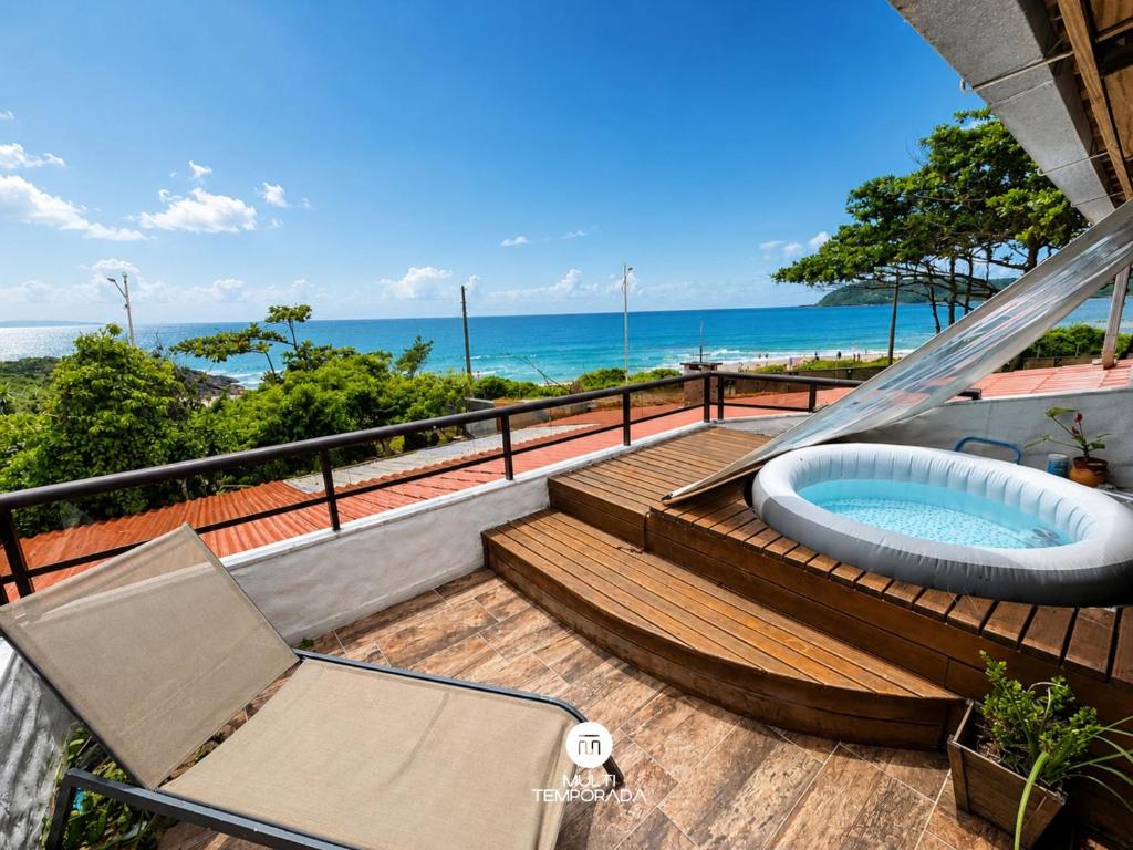 a balcony with a hot tub and a chair and the ocean at Pousada Ondas da Grande - Penha/SC in Penha