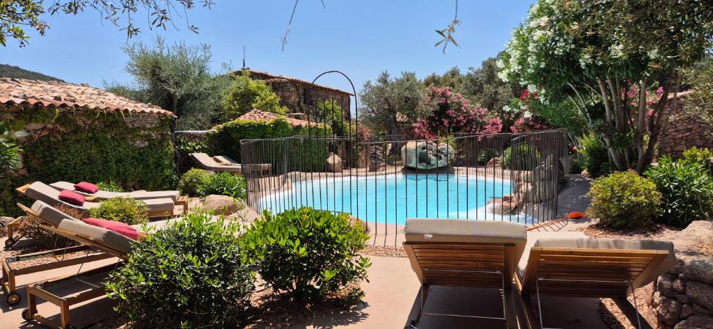 a swimming pool in a yard with chairs and a fence at Ranch Campo Palombaggia in Porto-Vecchio
