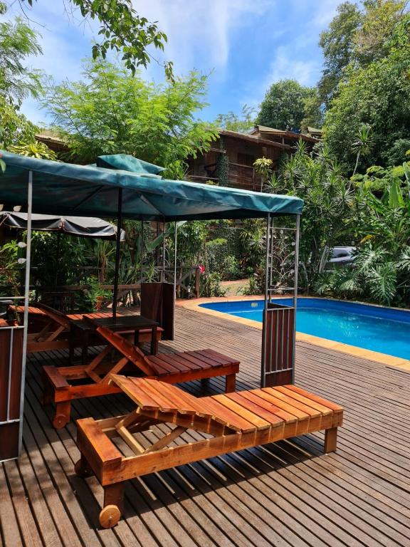 Eine Terrasse mit Bänken und einem Sonnenschirm neben einem Pool in der Unterkunft Hotel Jasy in Puerto Iguazú