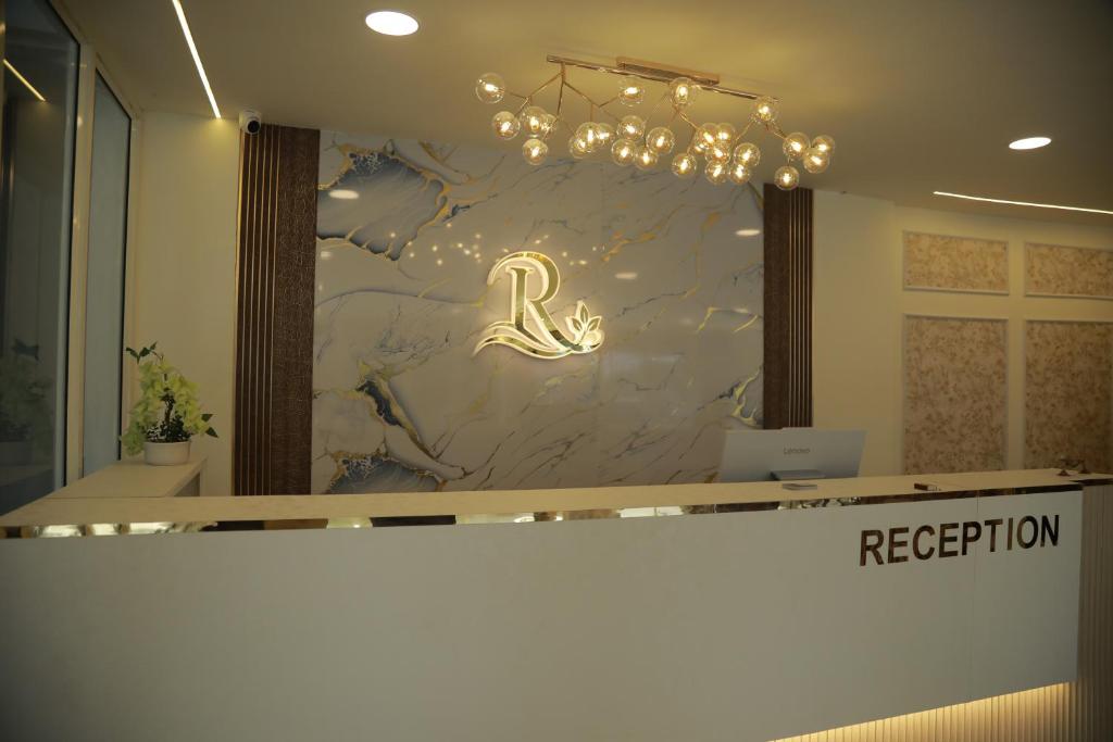 a reception area with a marble wall with a chandelier at Rivayn Suites in Thiruvalla