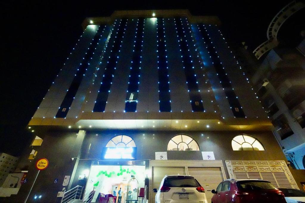 a tall building with blue lights on it at فندق ندى الفيروز in Az Zāhir