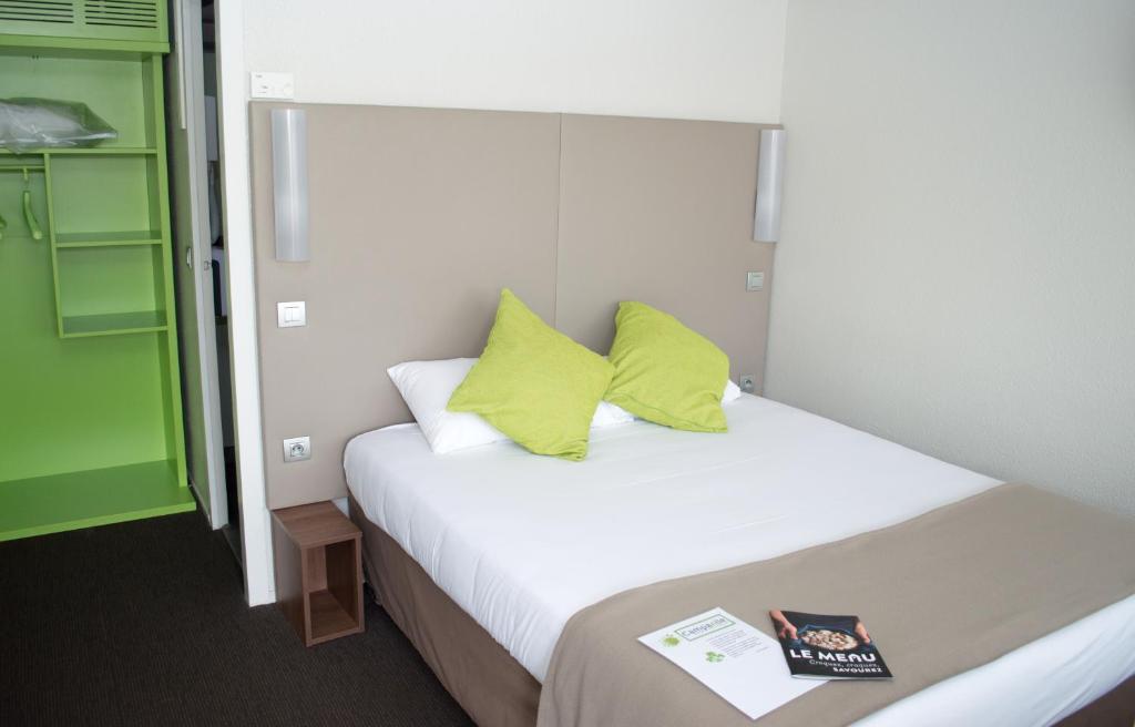 Un dormitorio con una cama con almohadas amarillas y un libro en Campanile Villeneuve-Sur-Lot, en Villeneuve-sur-Lot