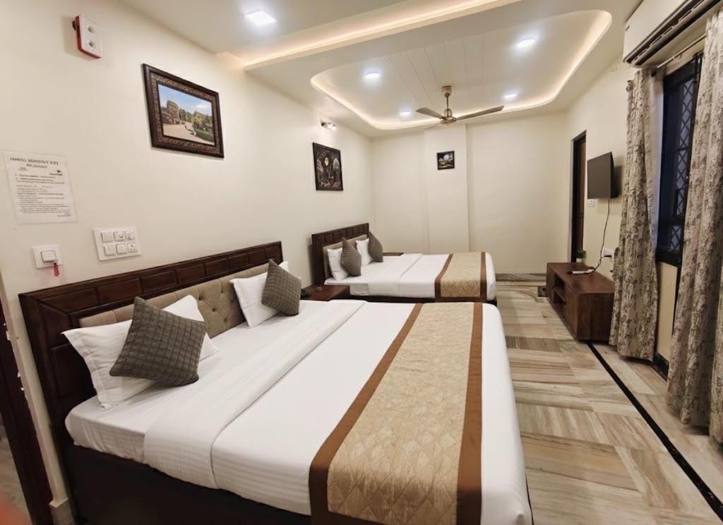 two beds in a room with white walls at Holiday Out hotel in Jodhpur