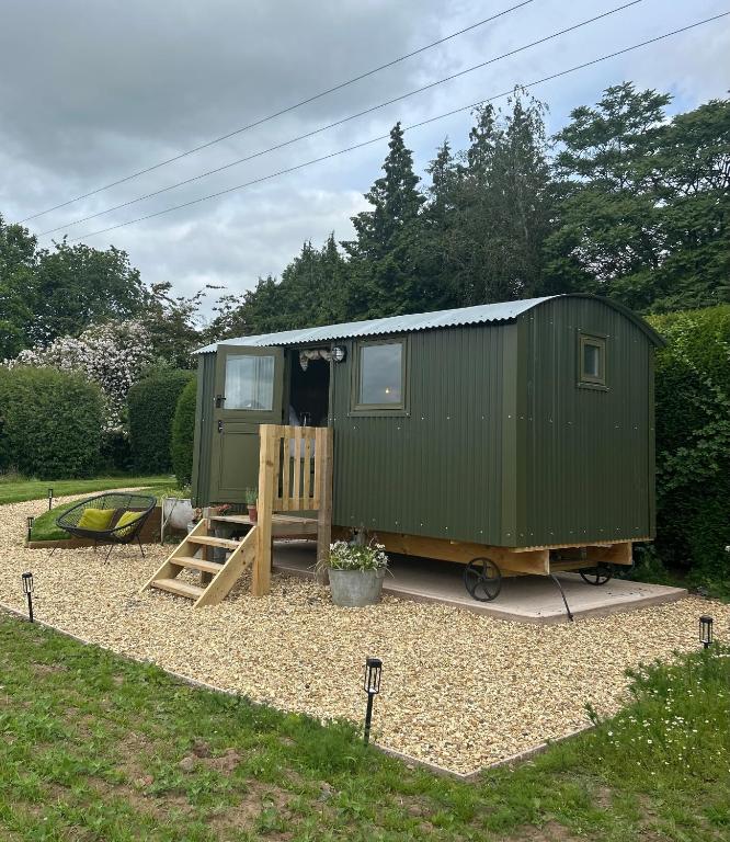 a green trailer with a wooden door in a yard at Shepherds Hut in Shropshire with Swimming Pool in Shifnal