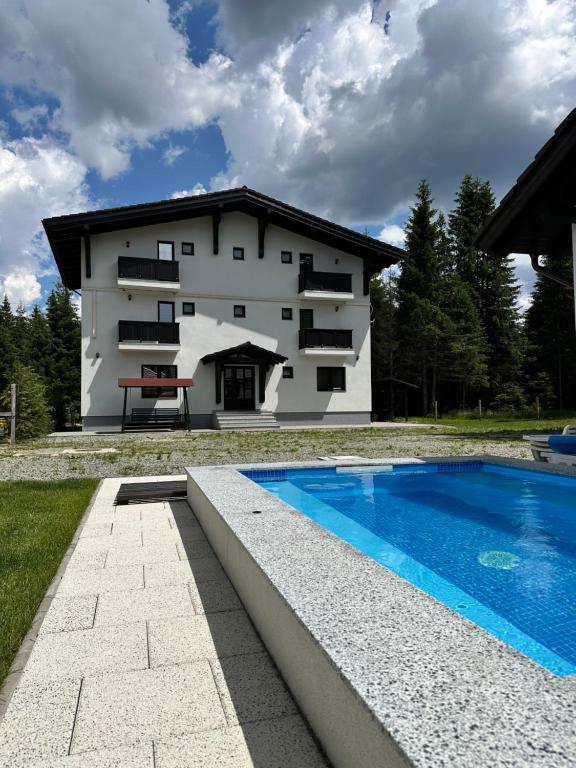 a house with a swimming pool in front of it at Cabana Mullerhaus in Tău Bistra