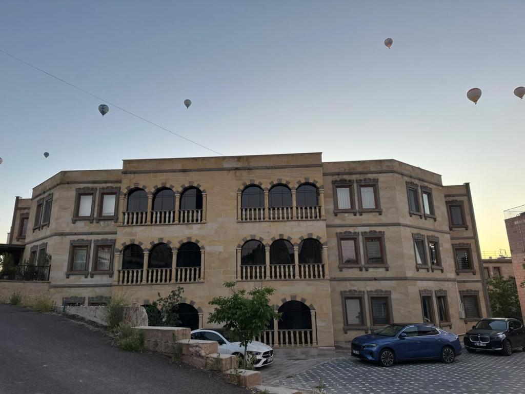 a large brick building with cars parked in front of it at Göreme Apartment in Göreme