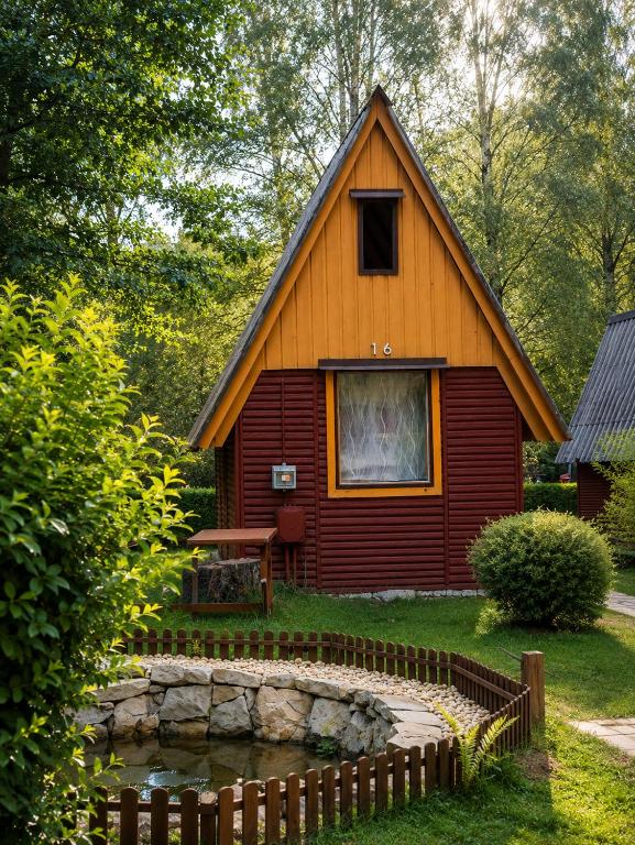 a small house with a pond in front of it at Kemp Sluníčko in Doksy