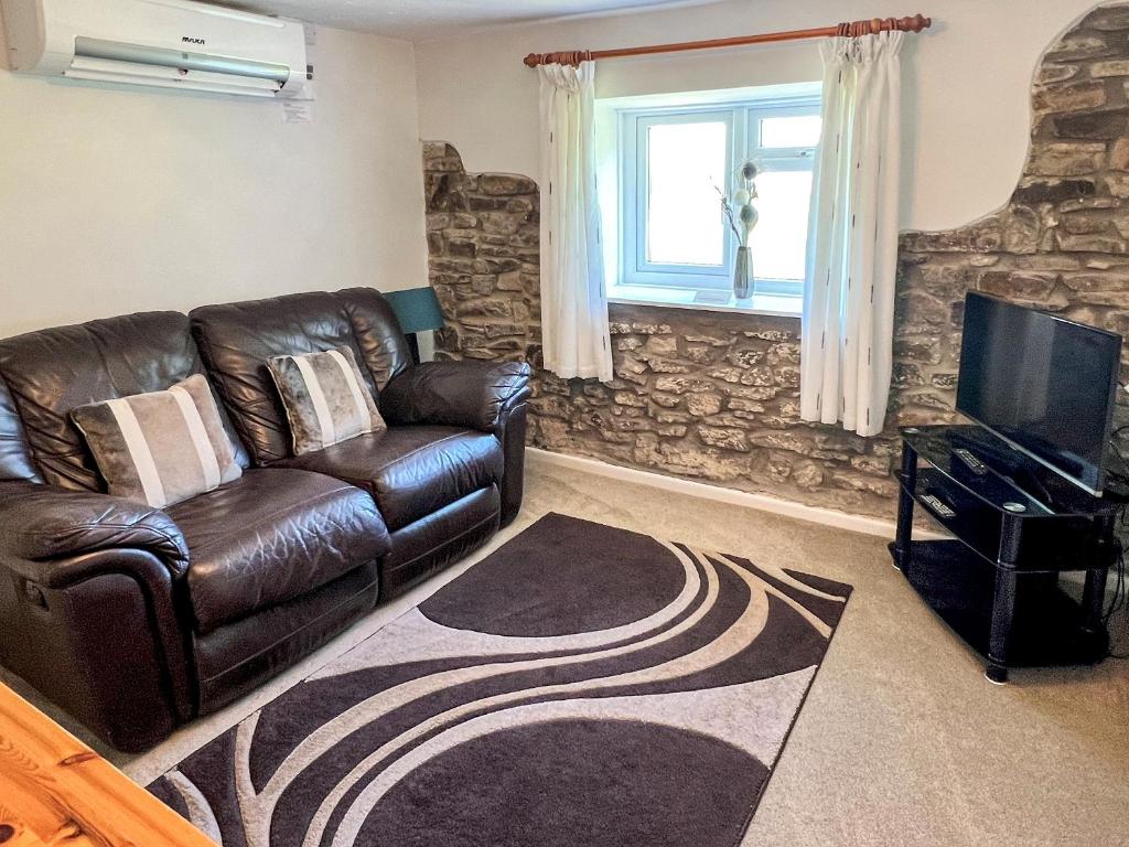 a living room with a leather couch and a television at Bramling Apartment - Uk49302 in Woolfardisworthy