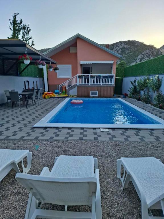 a swimming pool with two chairs and a house at Villa Počitelj in Čapljina