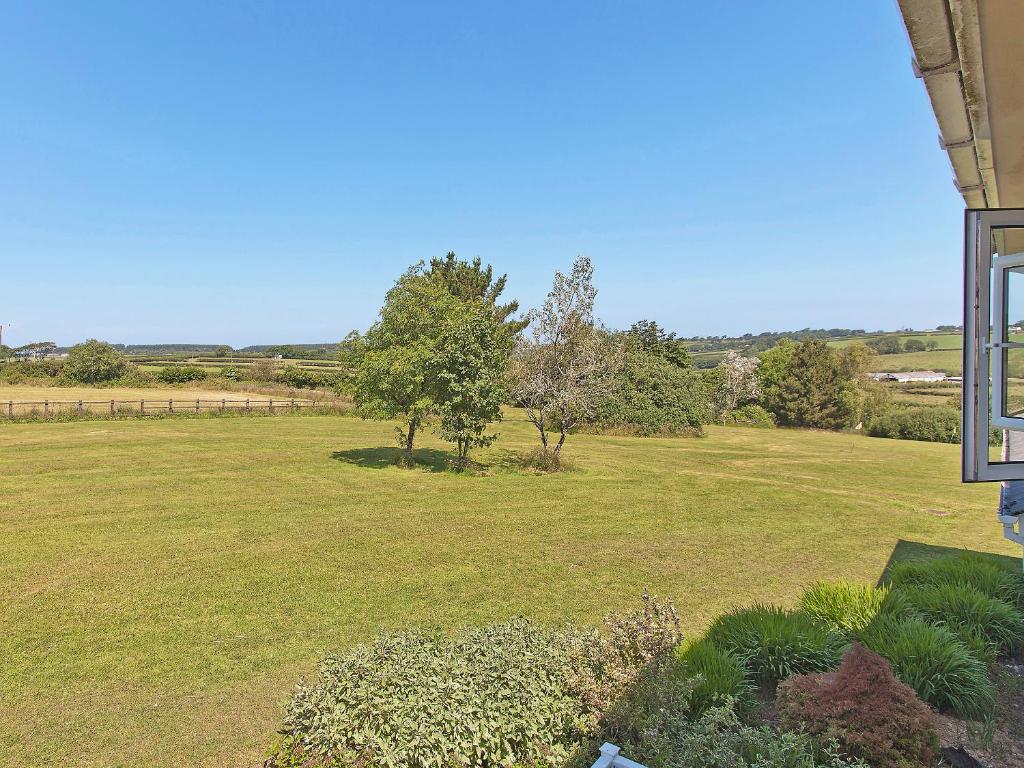 a large field of grass with trees in the background at Chestnut Apartment - Uk49277 in Woolfardisworthy