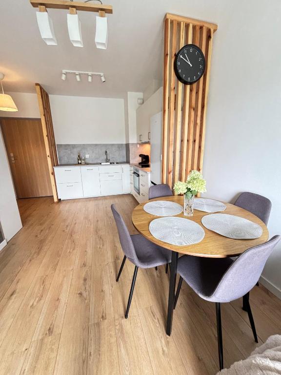 a dining room with a table and chairs and a clock at Marigold Apartment Łódź in Łódź