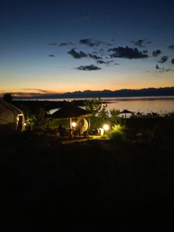 a sunset on a beach with an umbrella and the water at Uort in Tossor