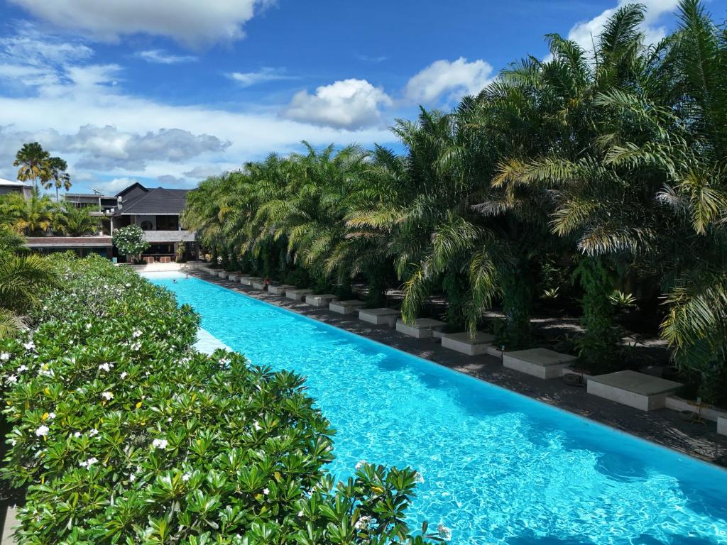 a swimming pool with palm trees in a resort at ONYX PARK RESORT Ubud in Ubud