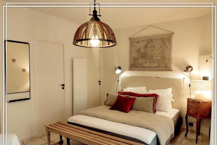 a bedroom with a bed and a pendant light at APPART HOTEL Place des Jolis Rêves in Riom-ès-Montagnes