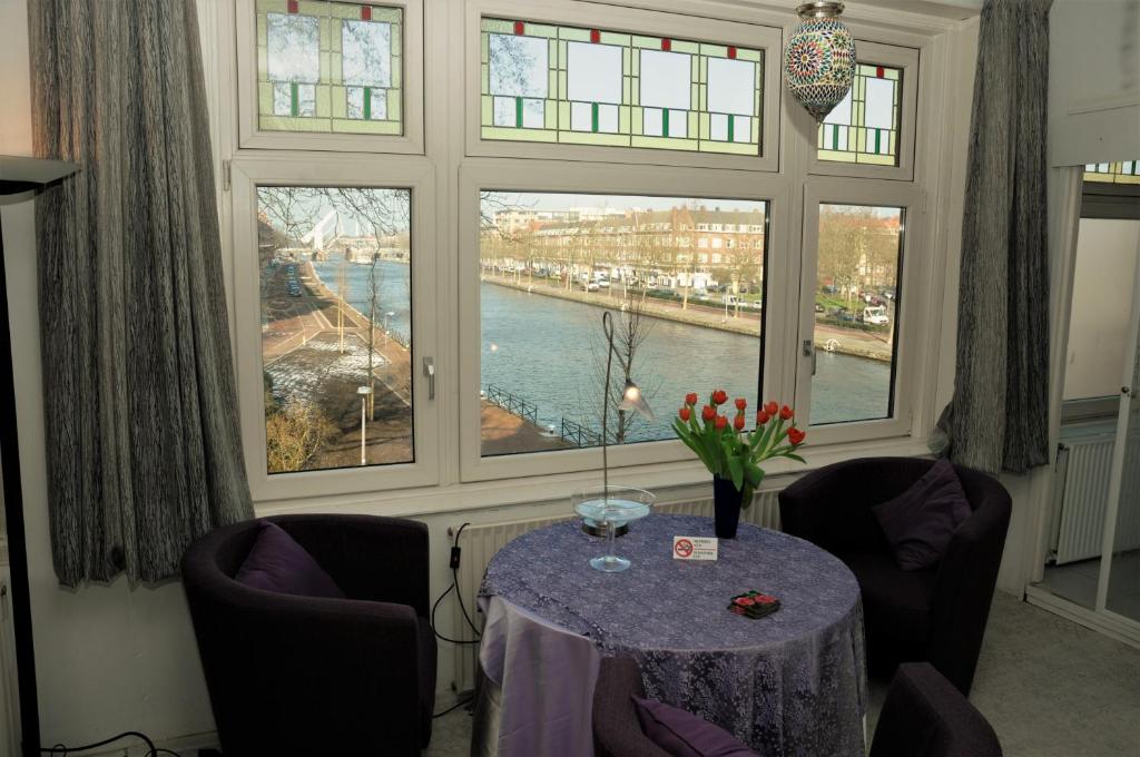 Zimmer mit einem Tisch, 2 Stühlen und Fenstern in der Unterkunft Sam's Place in Rotterdam