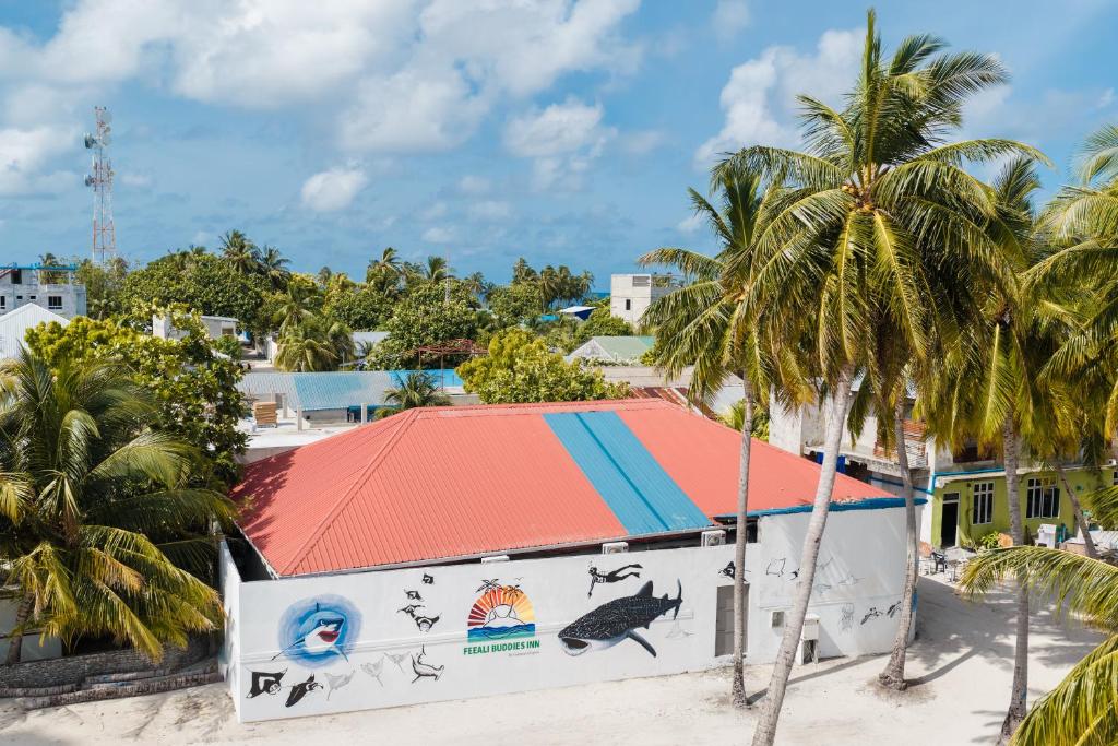 a building on the beach with palm trees at Feeali Buddies Inn in Maldive Islands