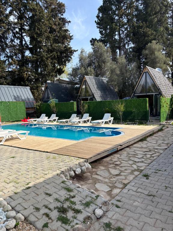 a swimming pool with lounge chairs and a house at BrothersHomes Bungalov in Duraliler