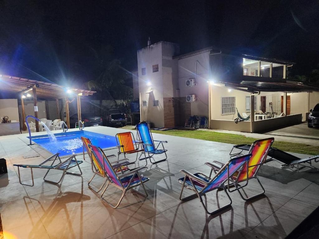 a group of chairs sitting around a pool at night at Recanto do mar in Ilhéus