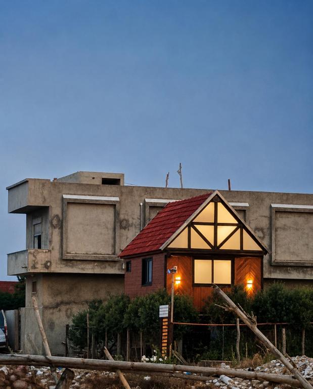 a small house with a red roof in front of a building at MiNi chalet en bois in Menzel Abderhaman