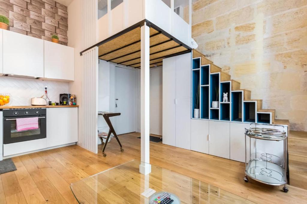 a living room with a staircase and a table at Appartement quartier St Michel climatisé près des quais avec parking in Bordeaux