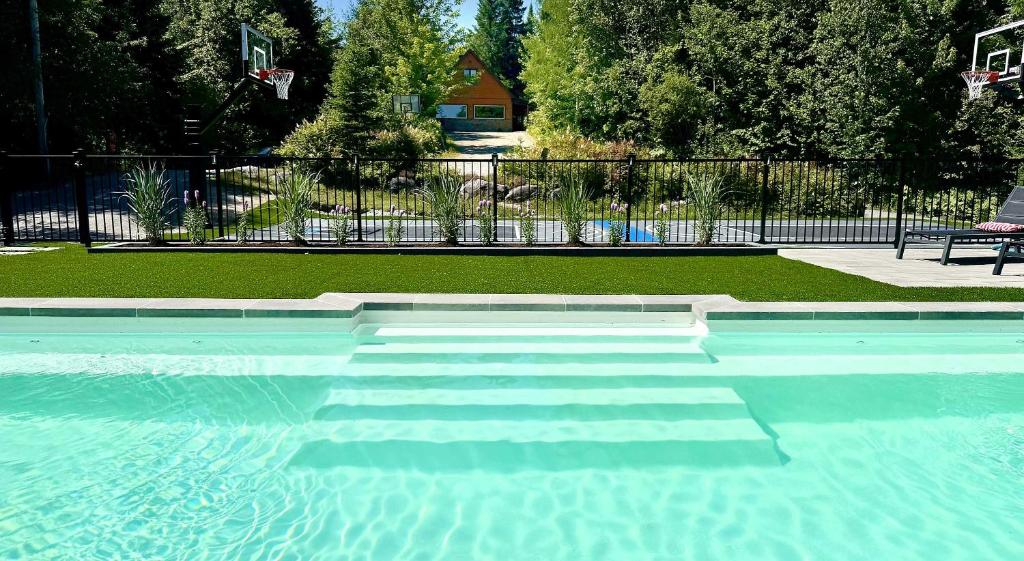 a swimming pool with blue water in a yard at Howard Lodge & Spa in Saint Adolphe D'Howard