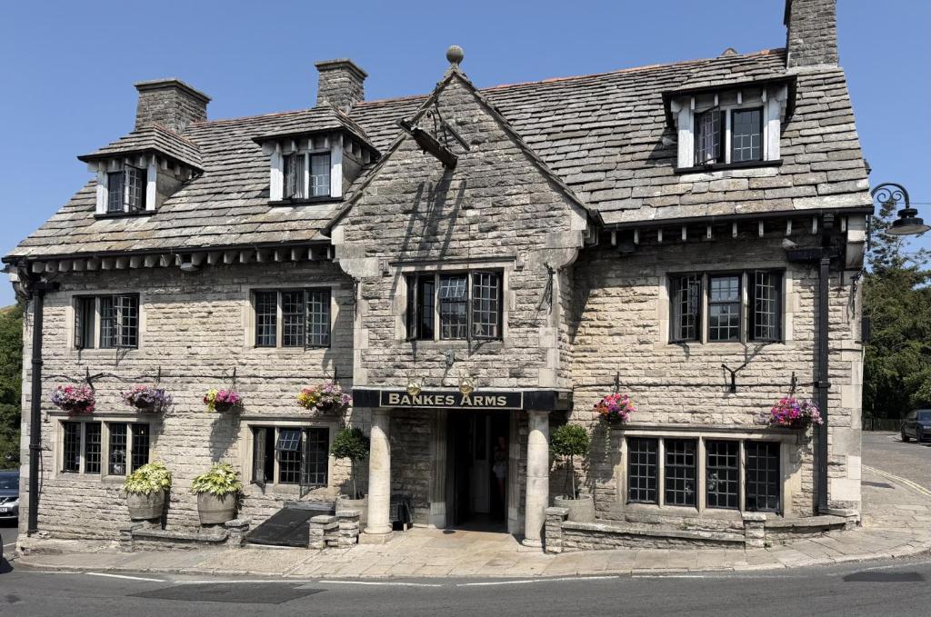 an old stone building with flowers in front of it at Bankes Arms Hotel in Wareham