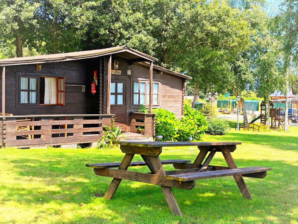 a picnic table in front of a small cabin at CAMPING A GRANDELLA in El Franco
