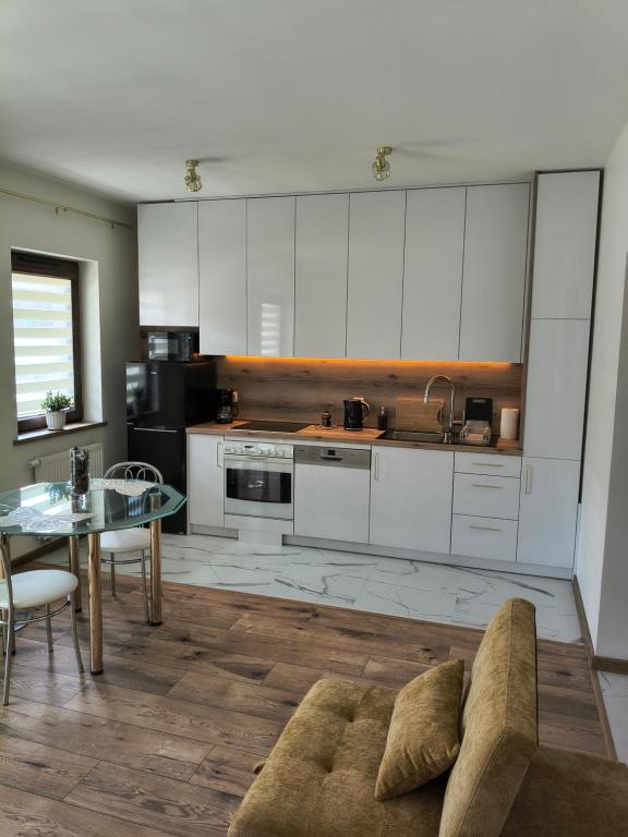 a kitchen with white cabinets and a table and a couch at Apartament przy Matce Polce in Łódź