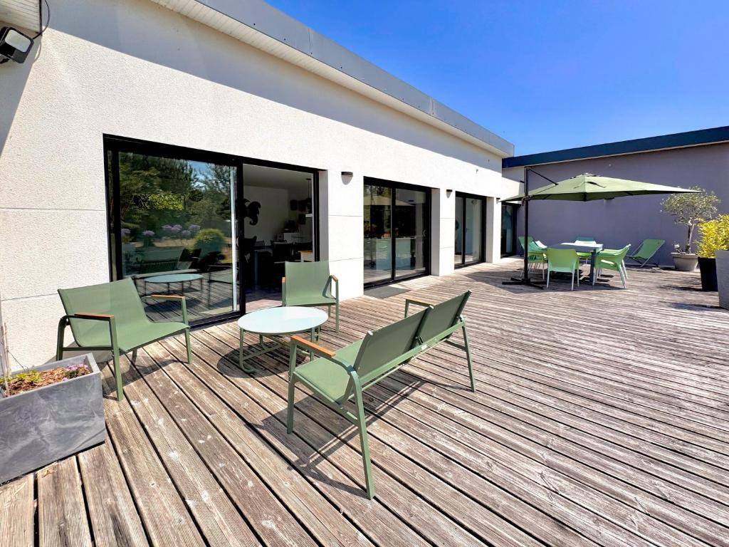 a wooden deck with tables and chairs on a building at La maison du verger in Loctudy