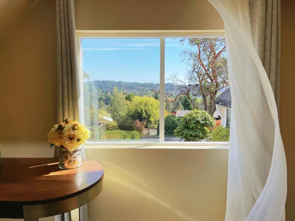 a window with a vase of flowers on a table at UVIC Ocean View Private Guesthouse in Victoria