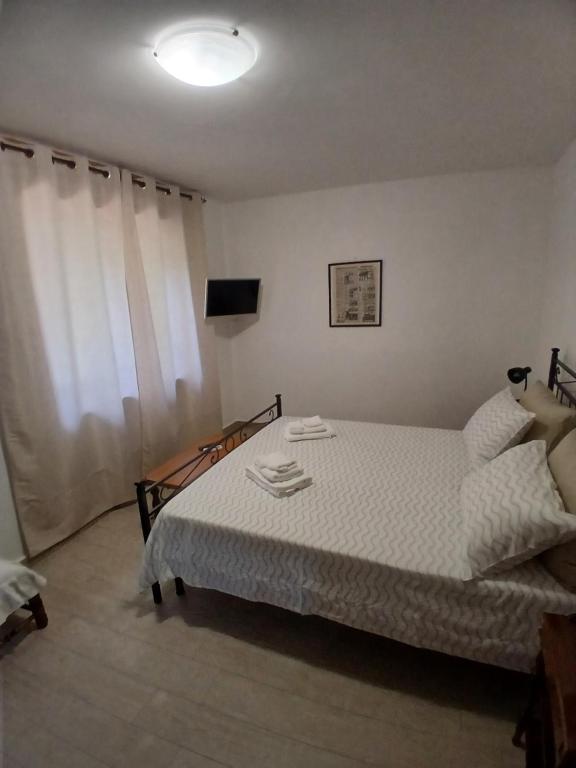 a bedroom with a bed with white sheets and a window at B&B ombra dei pini in San Leucio del Sannio