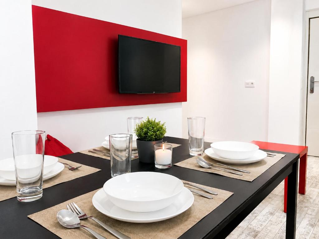 a dining room table with white plates and a red wall at Smart-Tech Plaza Apartment in Salamanca