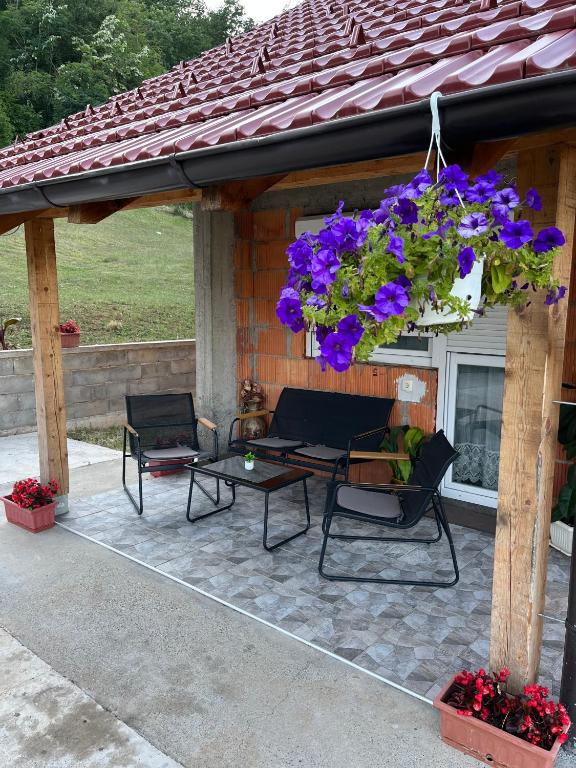 a patio with a table and chairs and purple flowers at Sumski Kutak in Valjevo
