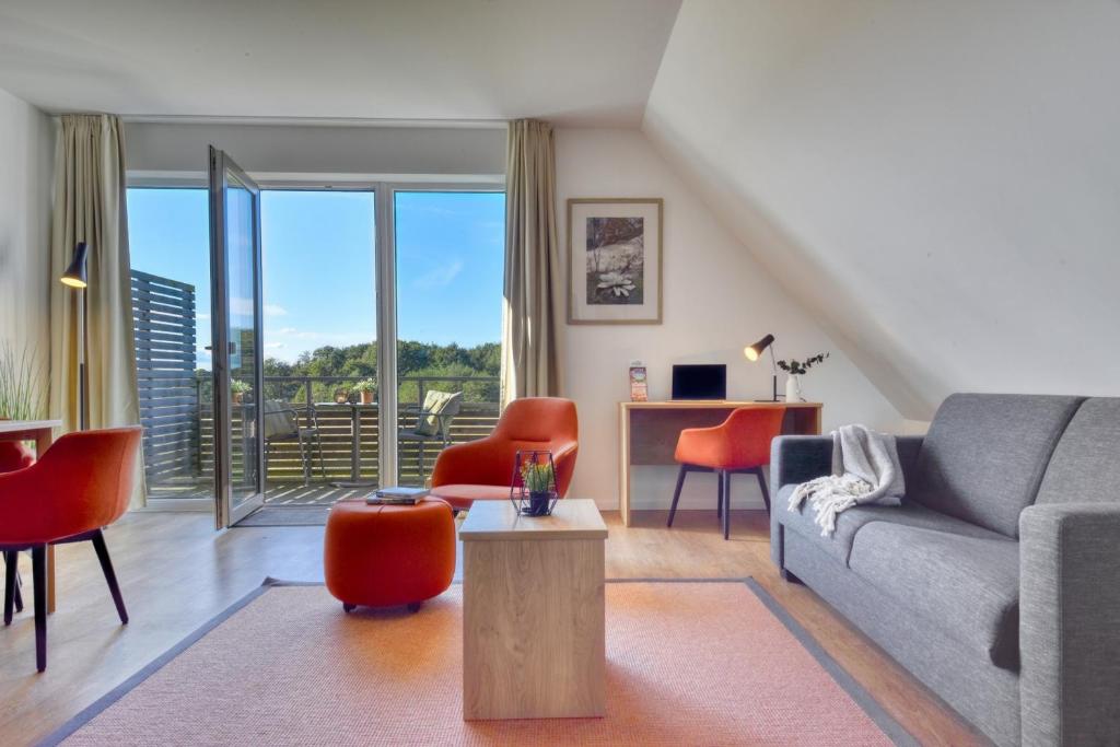 a living room with a gray couch and orange chairs at Ferienwohnung Buntspecht 31 im Wreecher Idyll Rügen by ruyastay in Putbus