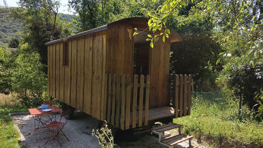 a wooden out house with a table in front of it at La Roulotte by Maison Maliga in Saint-Pierre-de-Curtille