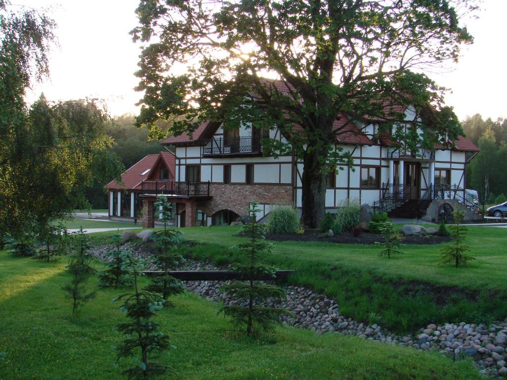 a large house with a tree in the yard at Jūrvingė in Žadvainai