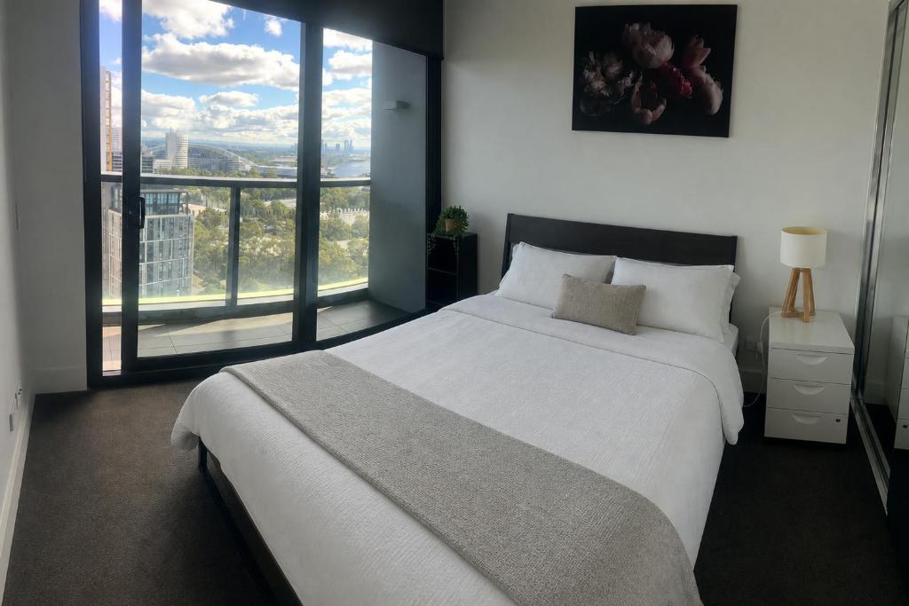 a bedroom with a large bed and a large window at Stadium View Retreat at Olympic Park in Sydney