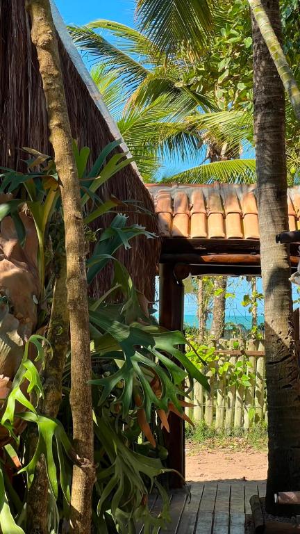 a wooden porch with a bench and palm trees at Zen Spa Caraíva in Caraíva