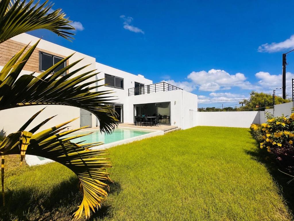 a white house with a yard and a swimming pool at Villa Marea Private Pool in Grand Baie with garden, BBQ & Parking in Grand-Baie