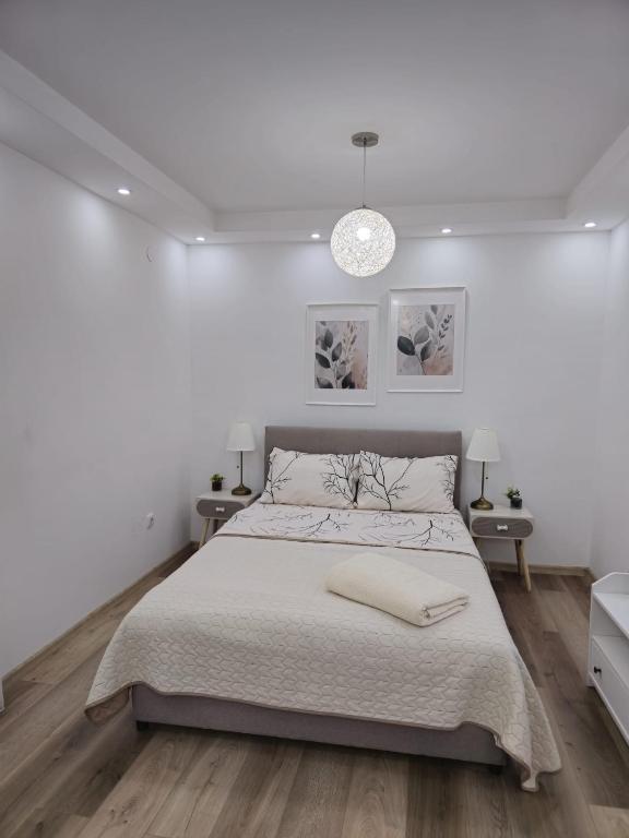 a white bedroom with a large bed and two tables at Alfi apartments 1 in Belgrade