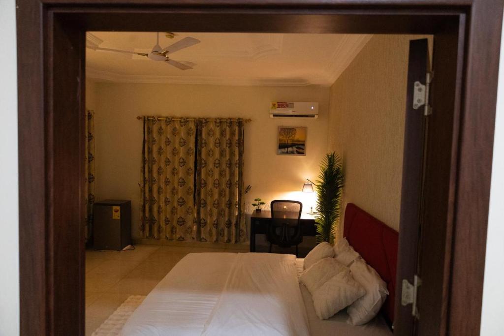 a bedroom with a bed and a room with a desk at Maya Lodge in Accra