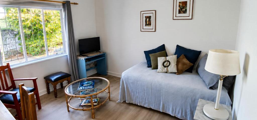a bedroom with a bed and a table and a window at Joe's Place Self-Catering in Windhoek
