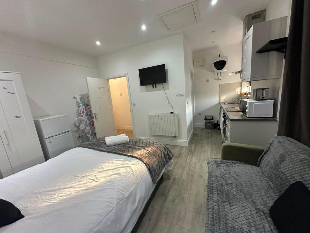 a bedroom with a bed and a couch and a tv at Wimbledon chase self- catering studio in Raynes Park