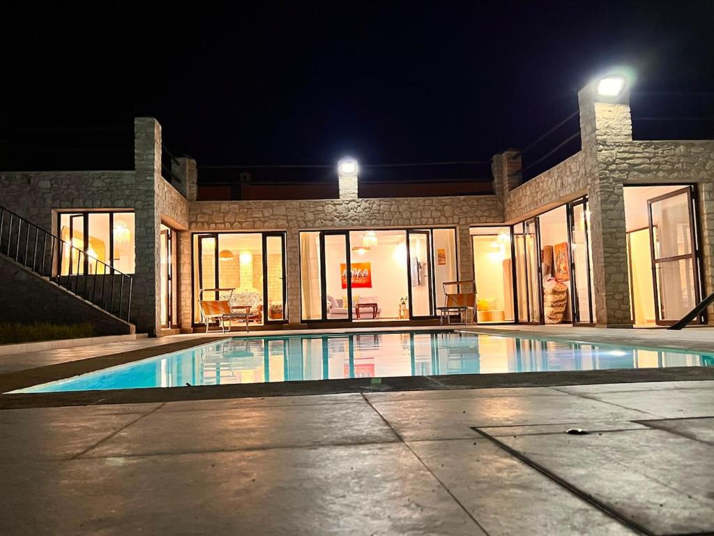 a large swimming pool in a house at night at Villa TaouBa in Ghazoua