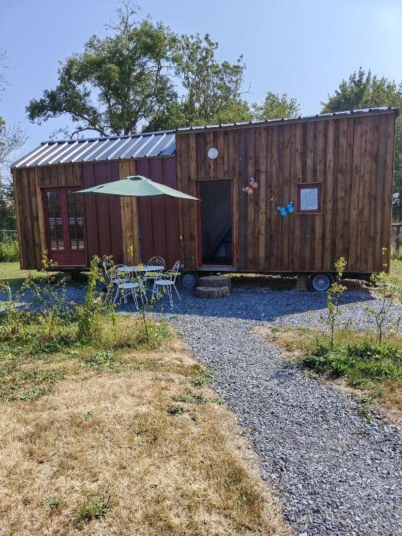 a wooden shipping container with a table and an umbrella at La tiny house in Bissières