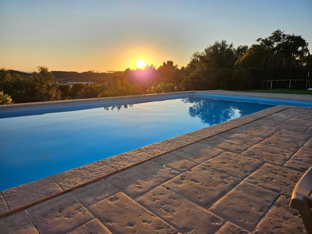 a swimming pool with the sunset in the background at Quinta do Penedo- Refúgio de Charme e Natureza in Ferreira do Zêzere