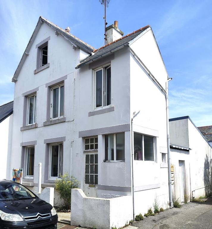a white house with a car parked in front of it at Maison entière Guilvinec in Le Guilvinec