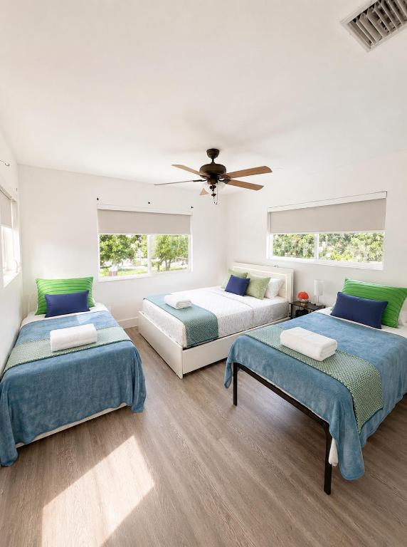 a bedroom with three beds and a ceiling fan at Cozy Private Triple Room in Design District Miami in Miami