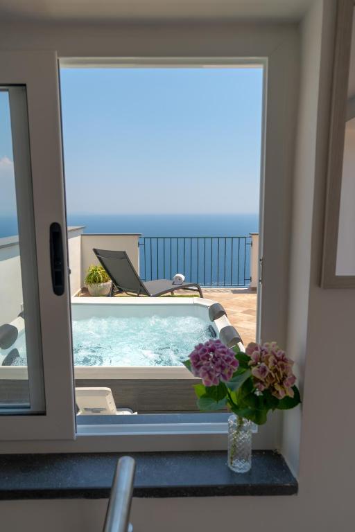 a vase of flowers sitting on a table next to a window at Santa Rosa Relais in Conca dei Marini